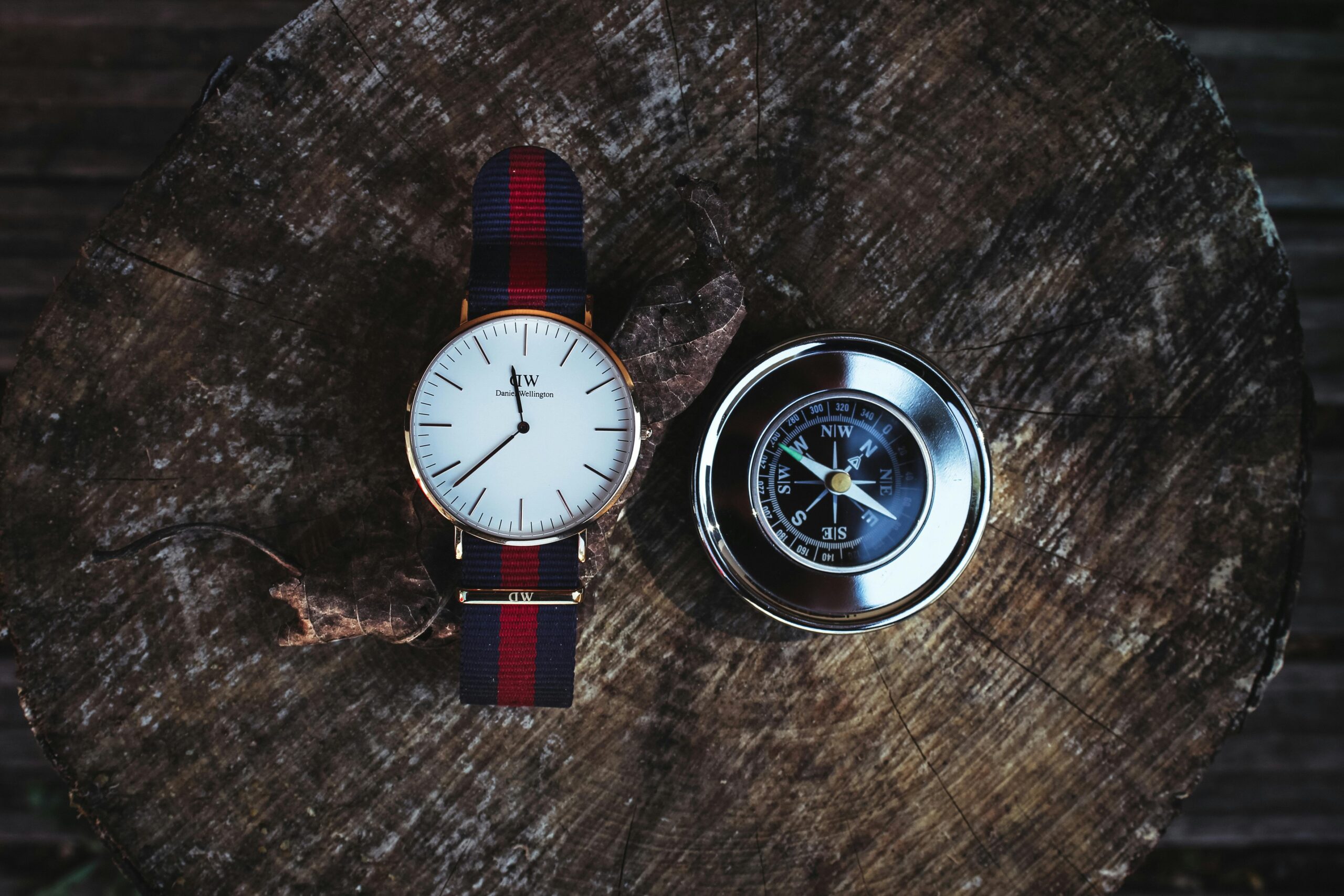 pexels-photo-691640-691640-1 A wristwatch and a compass placed on a wooden stump, captured from above.